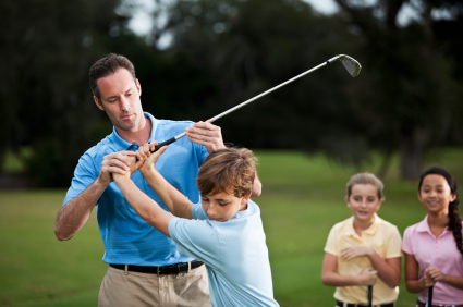 Golf instructor adjusting boy's grip